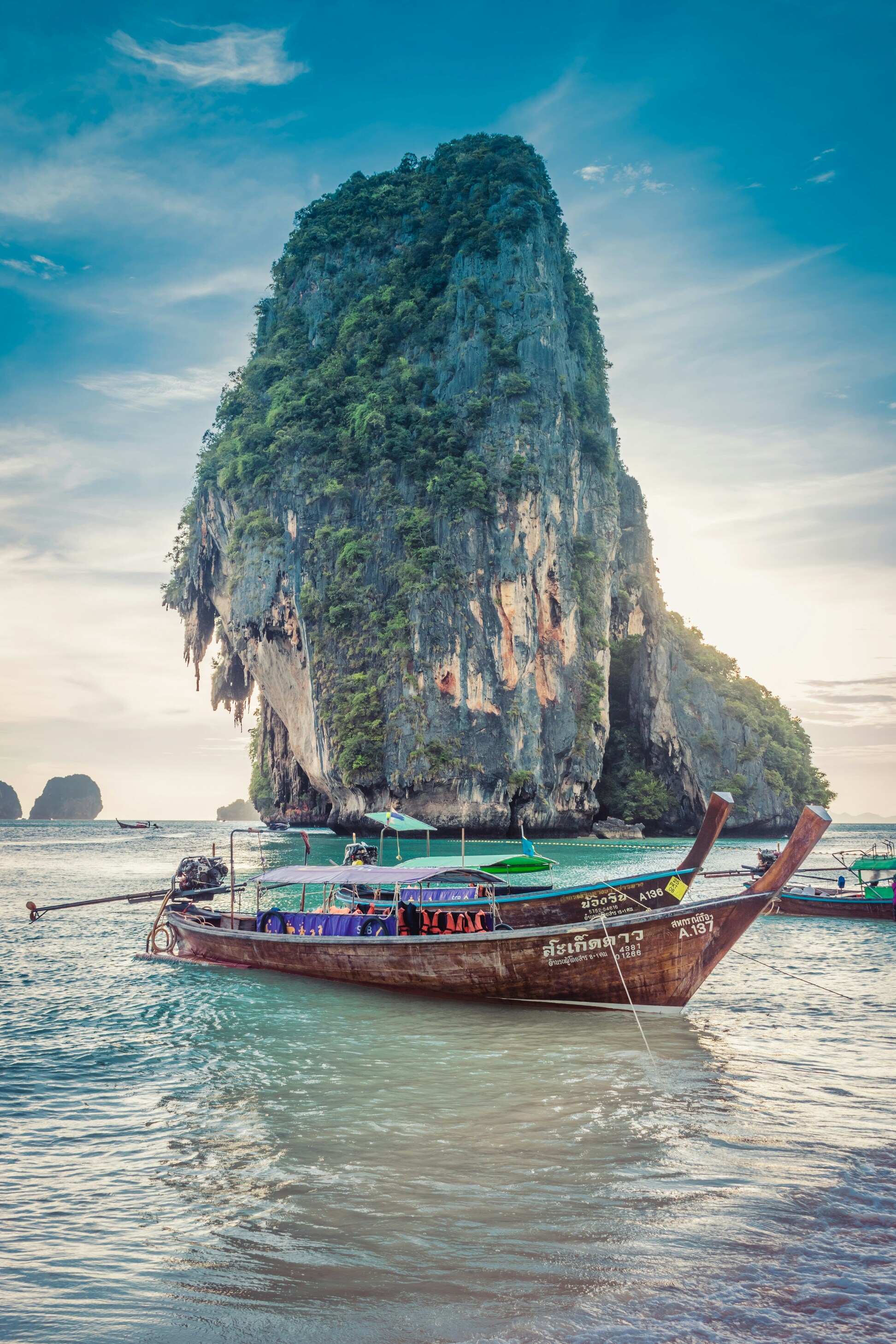 Longtail boats moored beneath a limestone cliff in Thailand